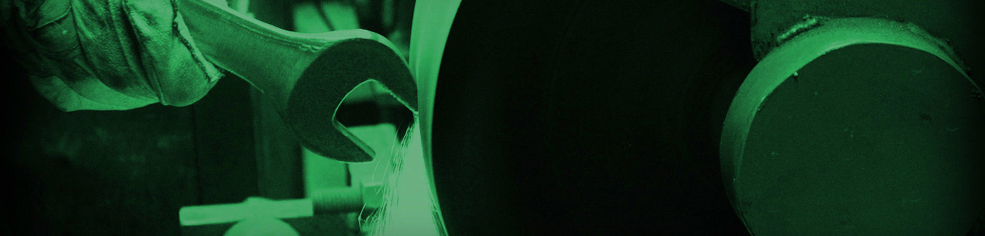 Close-up of a wrench being used on a mechanical part with a green filter.